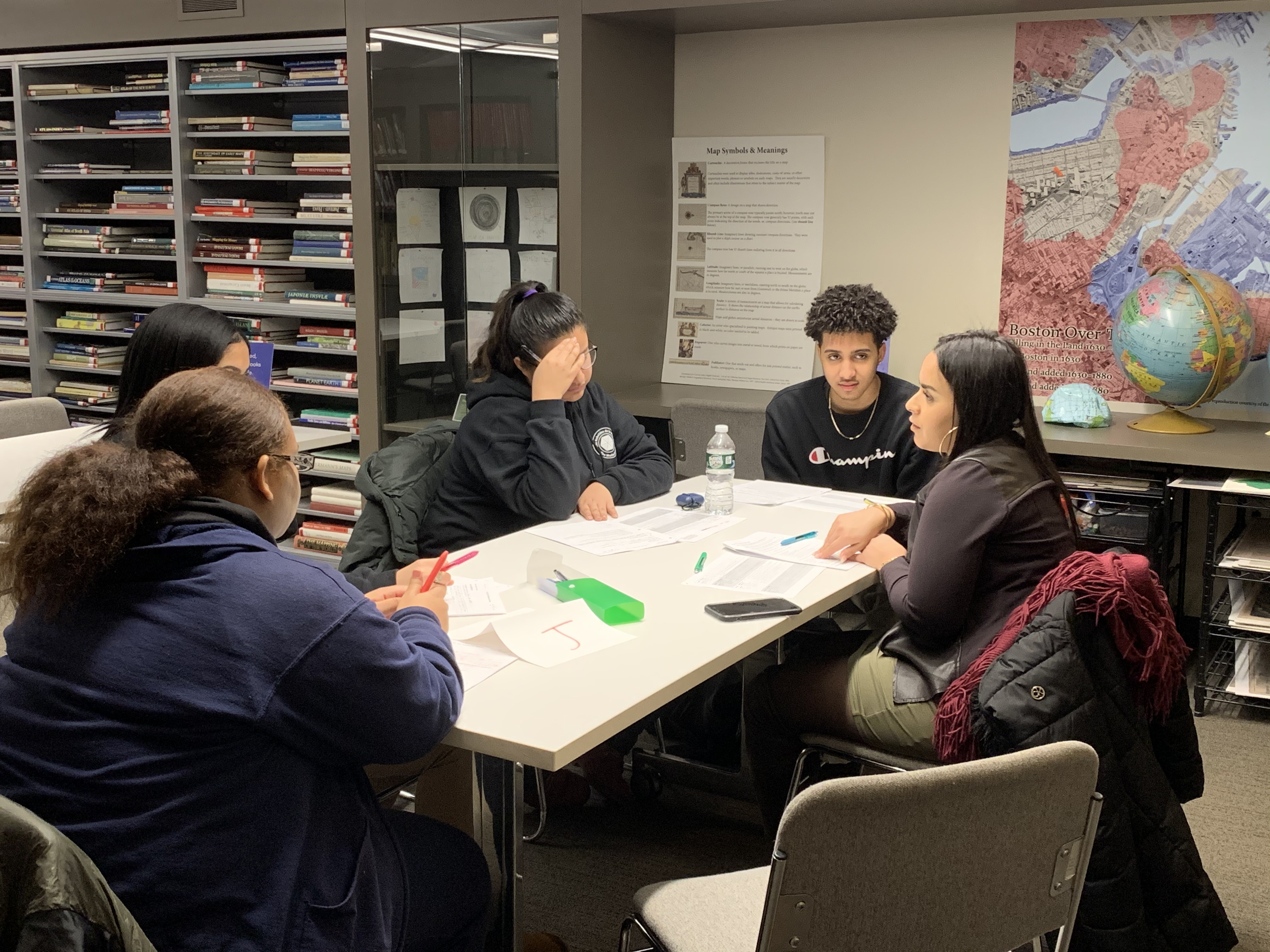 Students working on research questions with community leader at the Map Center